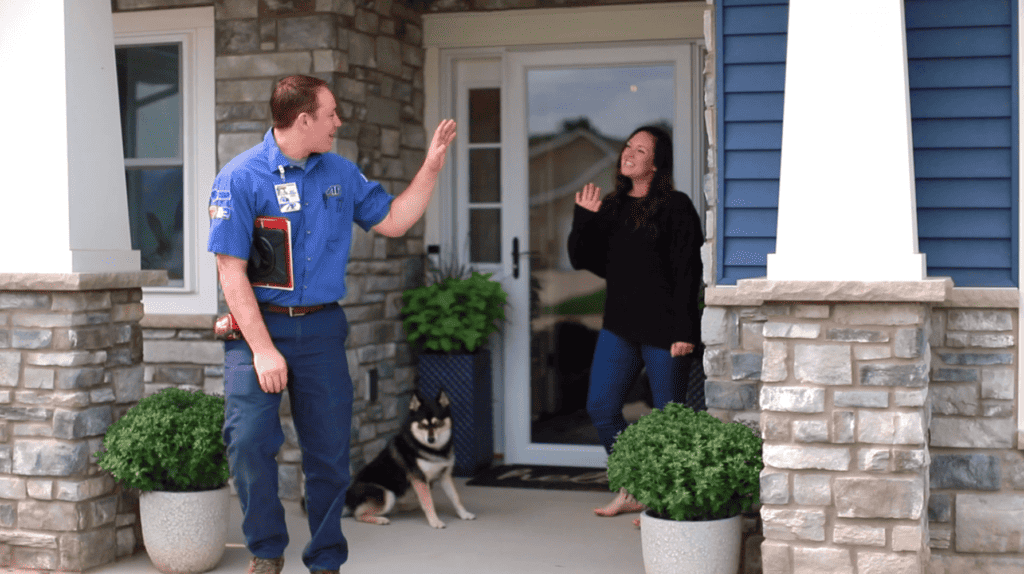 Plumber leaving the home of customer waving to her on the porch